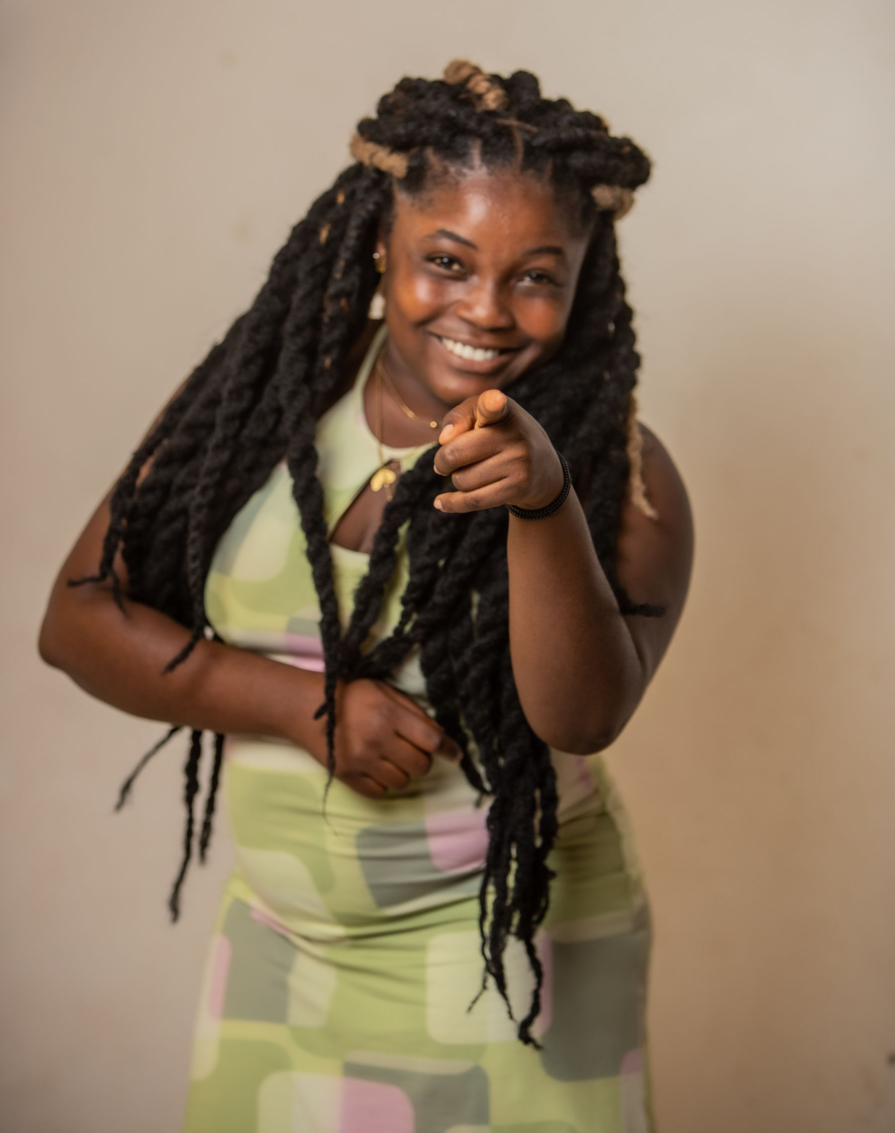 Smiling woman with long locs pointing at the camera